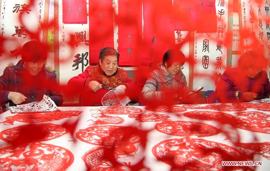 People cut the Chinese character "Fu" , or "happiness", in Fuyuyuan Committee of Quanhe Street in Huairou District, Beijing, capital of China, Jan. 17, 2013. The committee will send the paper-cuts of "Fu" to families as a gift for the coming Spring Festiva. (Xinhua/Bu Xiangdong) 