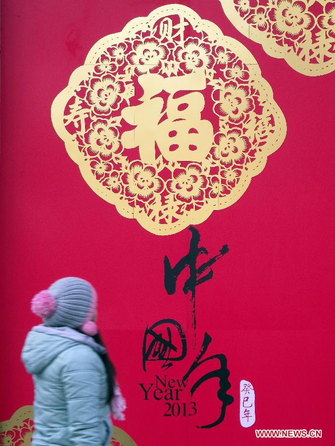 A woman looks at a wall decorated with the artworks of paper-cut in the Xinjiekou business district in Nanjing, capital of east China's Jiangsu Province, Jan. 17, 2013. Stores and shops in the Xinjiekou business district were decorated with holiday items to welcome the coming Spring Festival. (Xinhua/Wang Qiming)