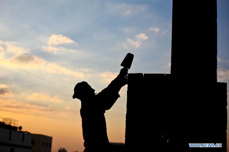 Nageh Marei builds a brick wall in an under-construction building in Cairo, capital of Egypt, Jan. 17, 2013. More than 40 years ago, Abdulzaher Marei left his hometown Atfeeh in Giza countryside and started to work in the construction field in Cairo. His four sons followed him. His eldest son Nageh is considered to be the leader of brothers in the field. He was married and has two children. Nageh and his family lives in the basement of an under-construction building with only one bed. Most of them sleep on the floor, and others spend the night in the street. Construction workers in Egypt has neither basic income nor health or medical insurance. They work with no safety methods, and their job owners often cut off their daily payment. (Xinhua/Amru Salahuddien)