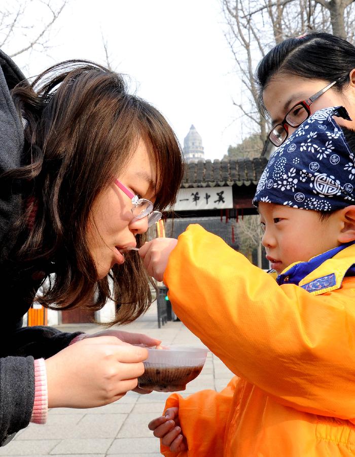 A boy feeds Laba porridge to a visitor in the senic spot of Huqiu Mountain in Suzhou, east China's Jiangsu Province, Jan. 17, 2013. Kindergarten Children together with their parents and teachers attended an activity to welcome the coming Laba Festival which falls on Jan. 19 this year. Laba festival, literally the eighth day of the twelfth lunar month, is considered the prelude of Chinese Spring Festival. (Xinhua/Hang Xingwei) 