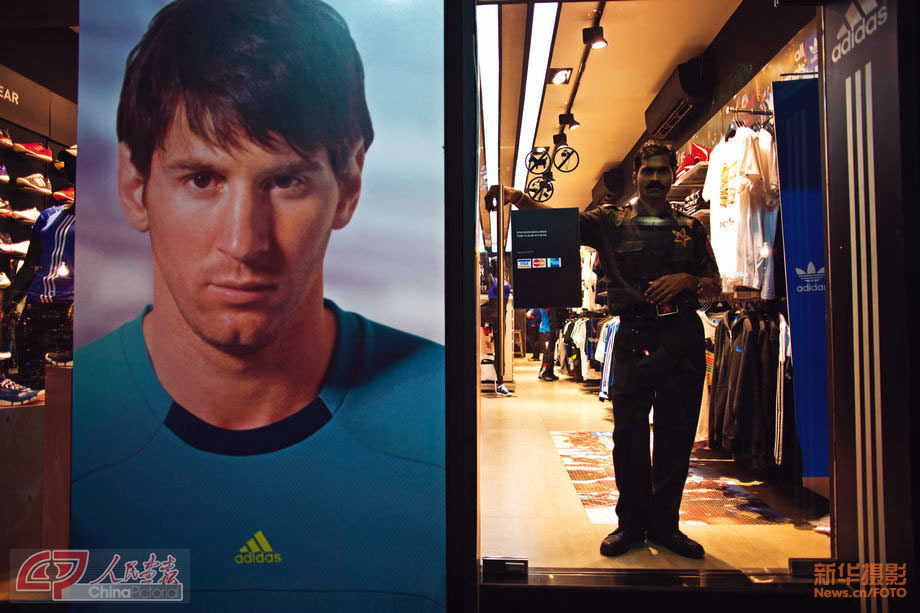 Photo shows a serious security guard standing at the door beside a huge poster of Lionel Andrés Messi, the famous Argentine footballer. (Chinapictorial/ Duan Wei)