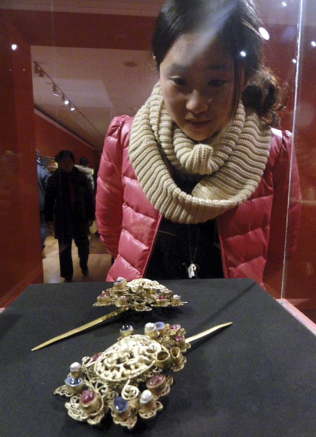 A visitor watches a pair of ancient golden hairpins during an exhibition of antiques of the 1573-1620 period at Suzhou Museum in Suzhou, east China's Jiangsu Province, Jan. 19, 2013. The exhibition, which showcases 108 antiques dating back to the 1573-1620 period, will last until April 14. (Xinhua/Wang Jiankang) 