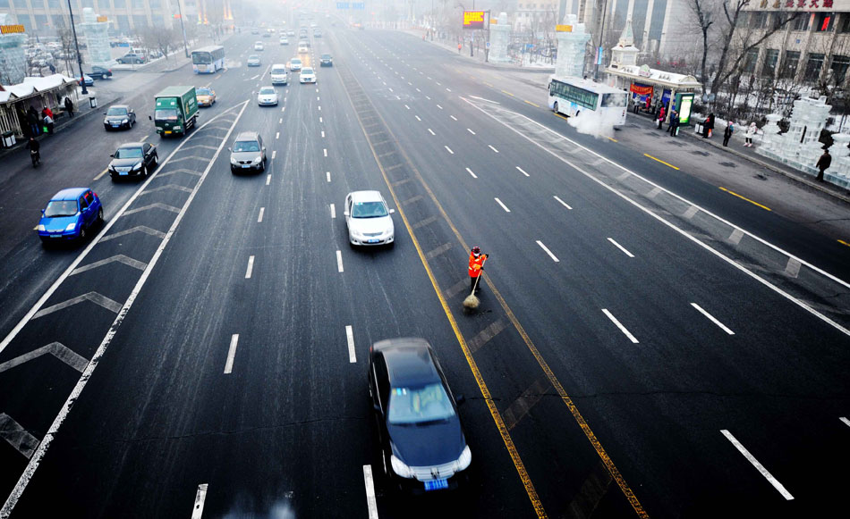 Yang Weixia, a sanitation worker, sweeps in the middle of a driveway in the freezing weather on Jan. 16, 2013. (Xinhua/Wang Jianwei)