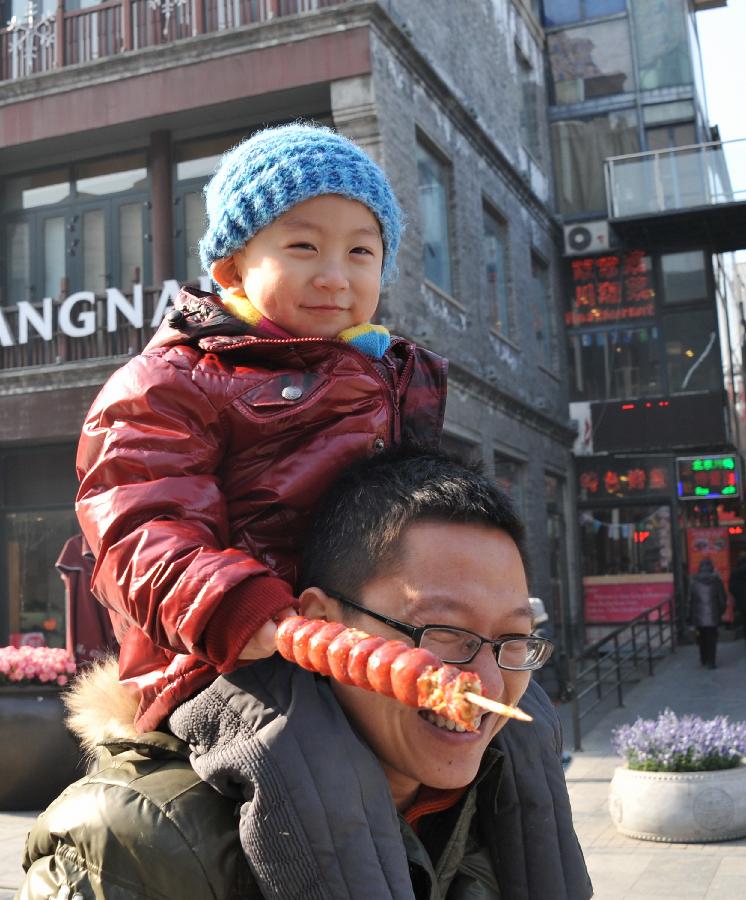 A man carries his son in the Qianmen Street in Beijing, capital of China, Jan. 21, 2013.  (Xinhua/Li Xin) 