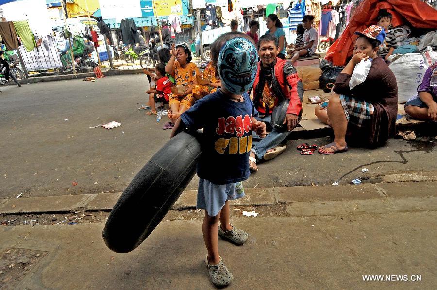 A boy wearing mask plays with a tire at a refugee camp in Otista, Jakarta, Indonesia, Jan. 21, 2013. Indonesia Health Minister Nafsiah Mboi underlined on Monday the importance of greater attention to flood victims, especially women and children coping with the current hardship in Jakarta. (Xinhua/Agung Kuncahya B.)