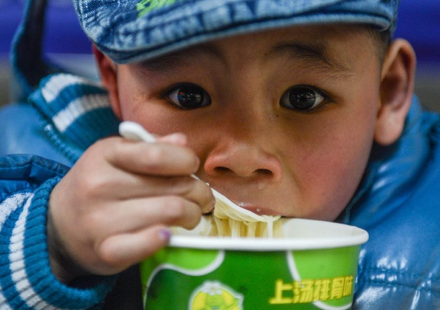 Zhao Yongchun, a five-year-old boy from Xi'an in northwest China's Shaanxi Province, eats instant noodles while waiting for the train at Hangzhou train station in Hangzhou, capital of east China's Zhejiang Province, Jan. 22, 2013. Zhao's parents now works in Yiwu of Zhejiang. Many migrant workers and their children have started to return home in order to avoid the Spring Festival travel peak that begins on Jan. 26 and will last for about 40 days. The Spring Festival, the most important occasion for a family reunion for the Chinese people, falls on the first day of the first month of the traditional Chinese lunar calendar, or Feb. 10 this year. (Xinhua/Han Chuanhao)