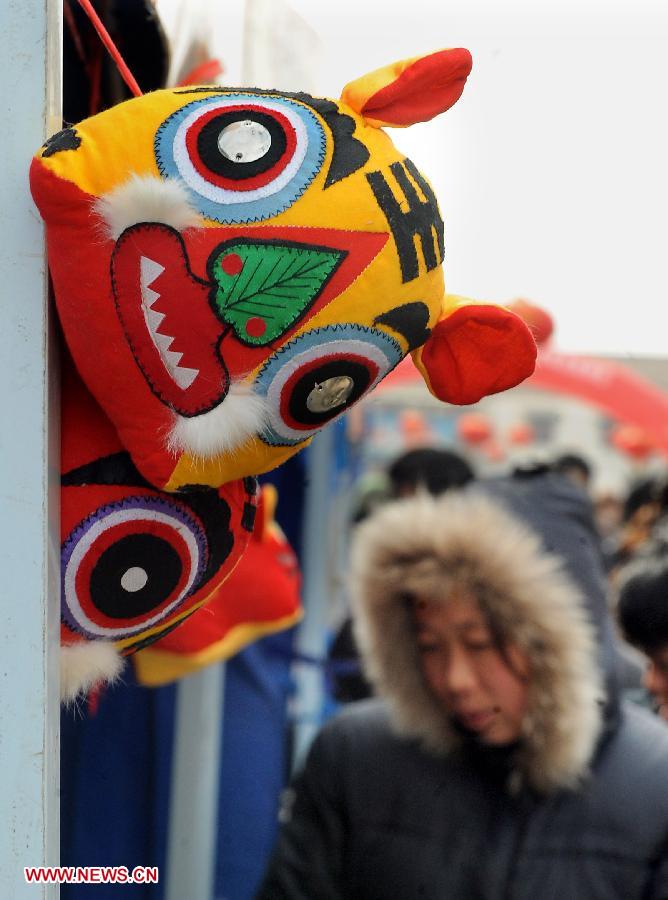 File photo taken on Feb. 26, 2010 shows a visitor walks past a cloth tiger crafts booth at a temple fair in Junxian County, central China's Henan Province. Temple fair in central China area is an important social activity for local people. The ancient temple fairs in central China were ceremonious sacrificial rituals. As time goes by, the focus of temple fair activities has shifted from "gods" to "people". The modern temple fair in central China is a platform of displaying folk culture as well as a channel for commodity circulation. According to statistics from the provincial cultural sector, there are about 35,000 temple fairs each year in Henan. (Xinhua/Wang Song)