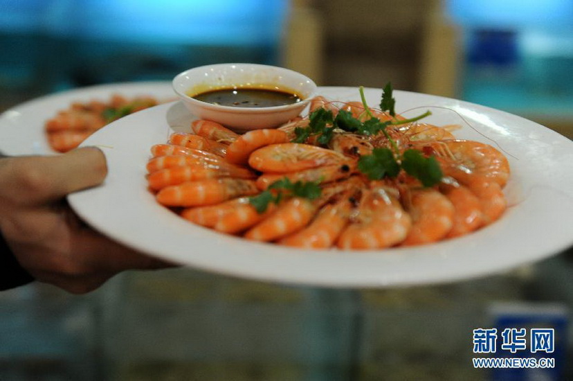 A waiter takes away sea-food dishes from dining table in a hotel in Zhengzhou, Jan. 20, 2013. On that day, 35 dinner tables for 400 people were arranged with each costing 1,499 yuan. (Photo/Xinhua)