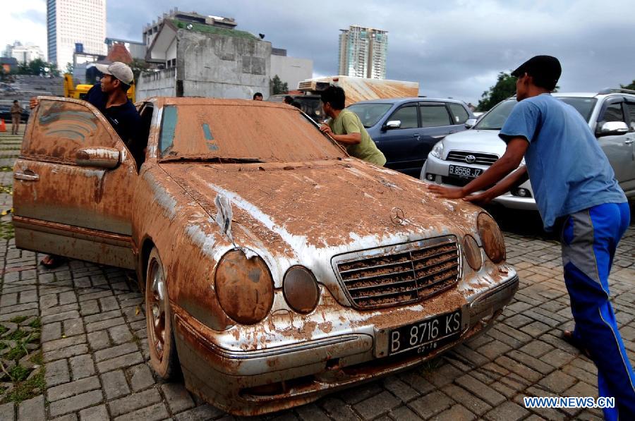 People evacuate a Mercedes-Benz car covered with mud from a flooded basement in Jakarta, Indoensia, Jan. 23, 2013. (Xinhua/Agung Kuncahya B.) 