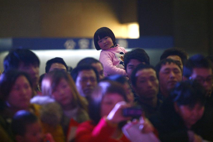 Passengers are seen during a performance presented by volunteers at the station in Hangzhou, capital of east China's Zhejiang Province, Jan. 23, 2013. A group of volunteers visited the train station in Hangzhou, offering the passengers hot ginger beverage, snacks and Spring Festival Couplets. Stations in Hangzhou embraced more passengers ahead of the Spring Festival travel peak. (Xinhua/Cui Xinyu) 