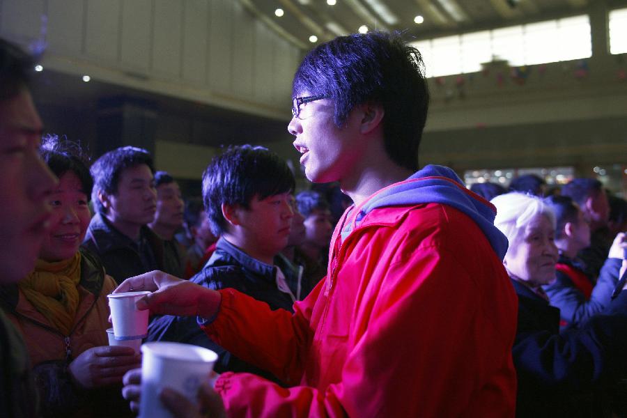 A volunteer offers the passengers hot ginger beverage at the station in Hangzhou, capital of east China's Zhejiang Province, Jan. 23, 2013. A group of volunteers visited the train station in Hangzhou, offering the passengers hot ginger beverage, snacks and Spring Festival Couplets. Stations in Hangzhou embraced more passengers ahead of the Spring Festival travel peak. (Xinhua/Cui Xinyu) 