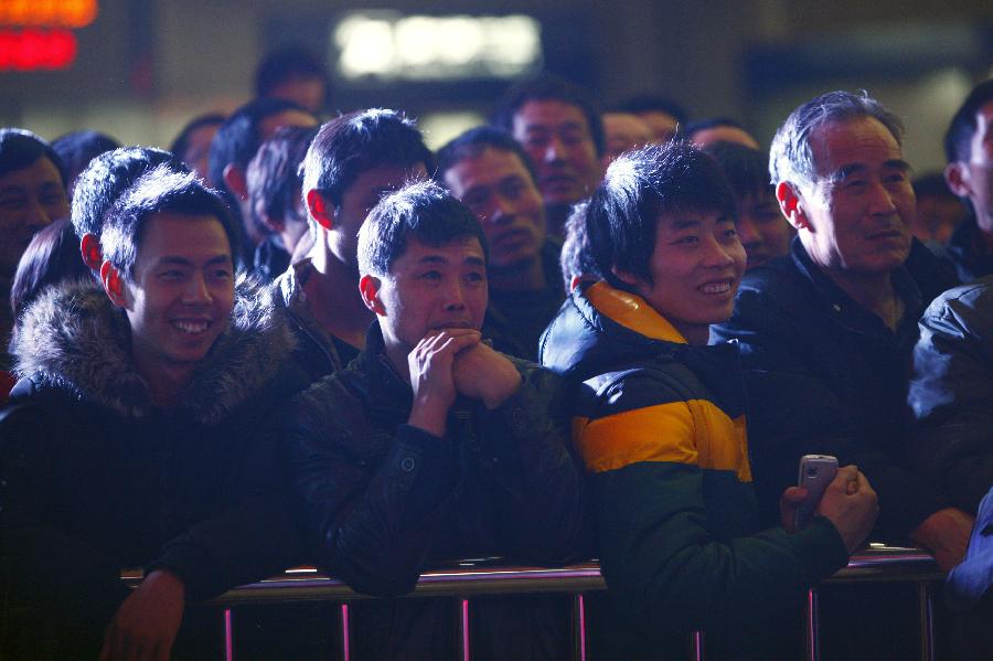 Passengers are seen during a performance presented by volunteers at the station in Hangzhou, capital of east China's Zhejiang Province, Jan. 23, 2013. A group of volunteers visited the train station in Hangzhou, offering the passengers hot ginger beverage, snacks and Spring Festival Couplets. Stations in Hangzhou embraced more passengers ahead of the Spring Festival travel peak. (Xinhua/Cui Xinyu) 