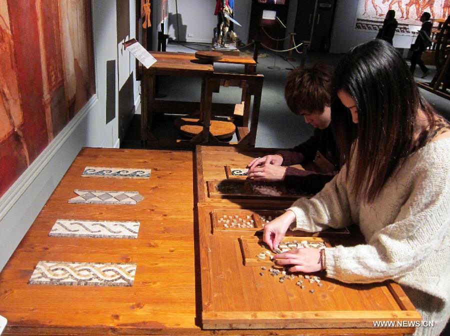 Visitors work on mosaic patches to experience the mosaic art of ancient Rome is seen during an exhibition at Hong Kong Science Museum in south China's Hong Kong, Jan. 23, 2013. Exhibition "Julius Caesar - Military Genius and Mighty Machines" is underway at the Hong Kong Science Museum. More than 40 exhibits reflecting the science and technology of ancient Romans were displayed on the show. (Xinhua/Zhao Yusi) 