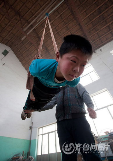 A boy makes a tough movement of acrobatics. (Photo/ Yx.iqilu.com)