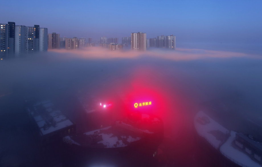 Dense fog hit back Beijing and caused serious air pollution on Tuesday and Wednesday. From the bird’s-eye view, the sleeping city was shrouded by fantasy created by shimmer of dawn, illumination and fog. (Photo/CCTV) 