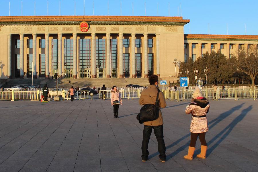 A visitor poses for photos in front of the Great Hall of the People in Beijing, capital of China, Jan. 24, 2013. (Xinhua/Wang Yueling) 