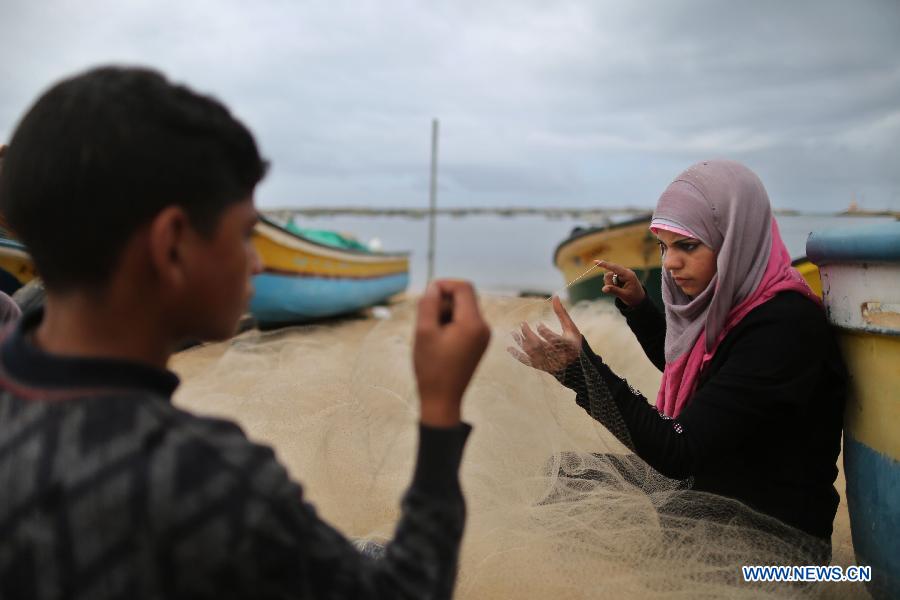 Palestinian fisherwoman Madeline Kolab repairs her fishing net on the sea beach in Gaza City, on Jan. 23, 2013. Sixteen-year-old Madeline Kolab is a fisherwoman. Her father, a veteran fisherman, became disabled, and therefore, she quit school after the ninth grade to take the job. "I don't care about what people say. I only care about feeding my family although fishing in Gaza is risky. The Israeli navy allows boats only a few miles offshore." Kolab said. (Xinhua/Wissam Nassar)