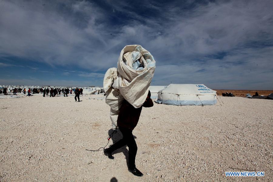 A relief worker move construction materials to build a tent in Zaatari refugee camp, near the desert town of Mafraq, northeast of Amman, Jan. 24, 2013. The past six days witnessed a record surge in the number of Syrian refugees seeking safety in Jordan. The number of refugees has pushed up the Syrian population in Jordan to around 300,000. (Xinhua/Mohammad Abu Ghosh) 