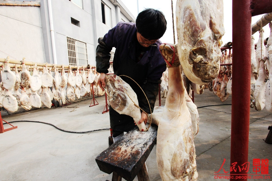 The worker shapes the ham by pickling it into the hold of the bench and straightening it.