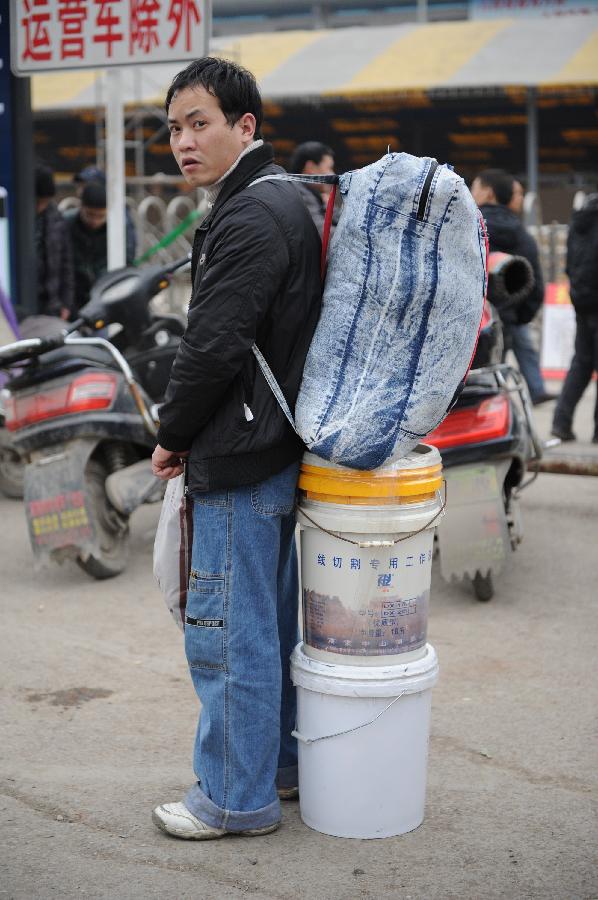 A passenger rests outside the Guiyang Railway Station in Guiyang, capital of southwest China's Guizhou Province, Jan. 23, 2013. The most important Chinese holiday, the Spring Festival, falls on Feb. 10 and migrants want to get home to see their families. The Ministry of Railways forecast the holiday travel rush, which starts on Jan. 26, will last until March 6. (Xinhua/Liu Xu) 