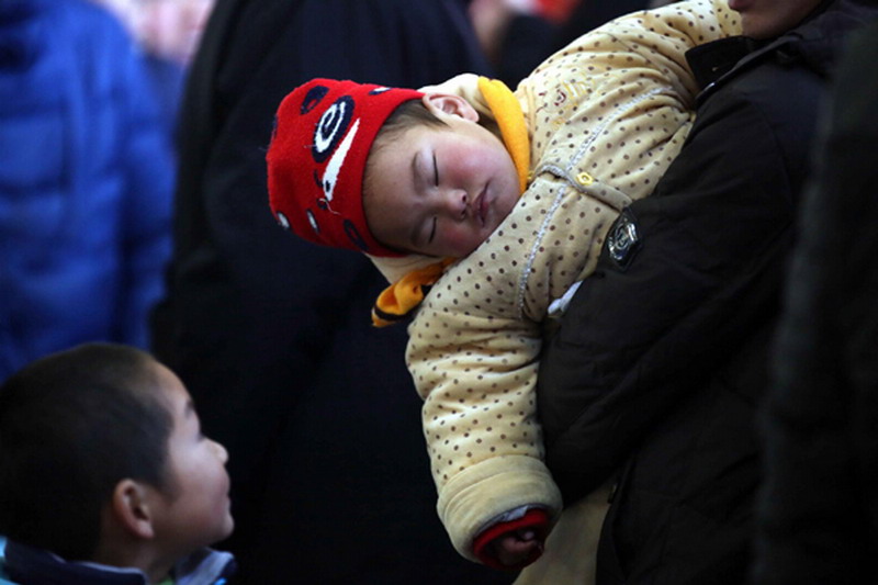 A man and his baby wait to board a train at Jinan Railway Station in Shandong province, Jan 26, 2013. (Photo/Xinhua) 