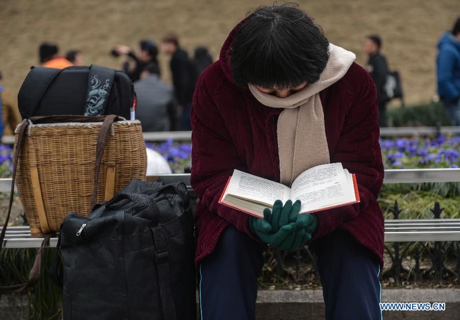 A woman reads while waiting for her train on the square of Hangzhou train station in Hangzhou, capital of east China's Zhejiang Province, Jan. 27, 2013. The 40-day Spring Festival travel rush began on Saturday. The Spring Festival, the most important occasion for a family reunion for the Chinese people, falls on the first day of the first month of the traditional Chinese lunar calendar, or Feb. 10 this year. (Xinhua/Han Chuanhao)