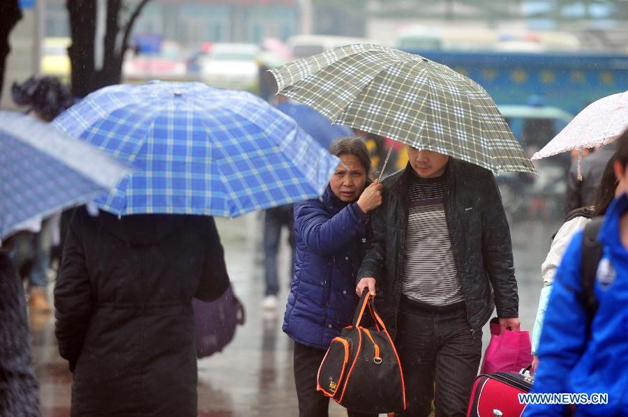 Passengers make their way to the railway station in the rain on the square of the Nanning Railway Station in Nanning, capital of south China's Guangxi Zhuang Autonomous Region, Jan. 26, 2013. As the Spring Festival, which falls on Feb. 10 this year, draws near, lots of people rushed to start their journey home. (Xinhua/Huang Xiaobang) 