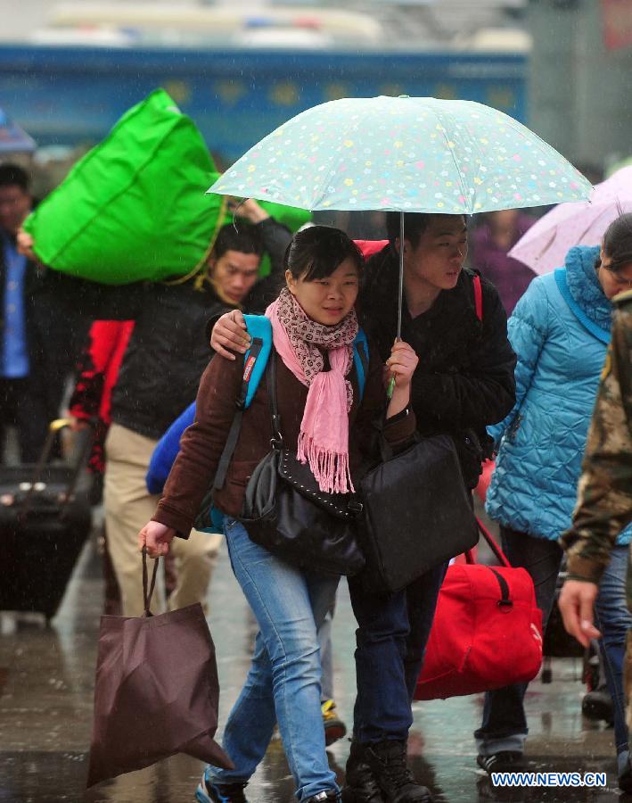 Passengers make their way to the railway station in the rain on the square of the Nanning Railway Station in Nanning, capital of south China's Guangxi Zhuang Autonomous Region, Jan. 26, 2013. As the Spring Festival, which falls on Feb. 10 this year, draws near, lots of people rushed to start their journey home. (Xinhua/Huang Xiaobang)