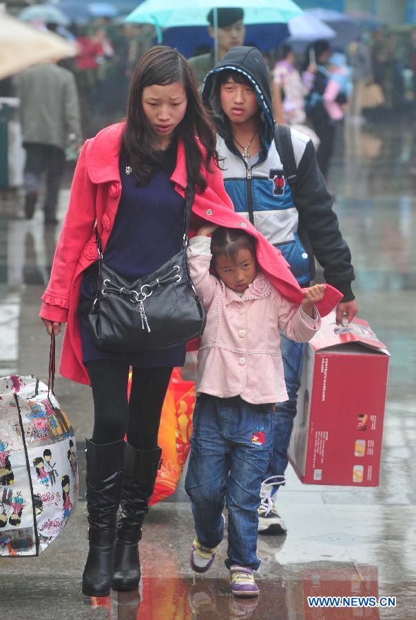 A girl hides in her mother's clothes to keep off the rain on the square of the Nanning Railway Station in Nanning, capital of south China's Guangxi Zhuang Autonomous Region, Jan. 26, 2013. As the Spring Festival, which falls on Feb. 10 this year, draws near, lots of people rushed to start their journey home. (Xinhua/Huang Xiaobang)