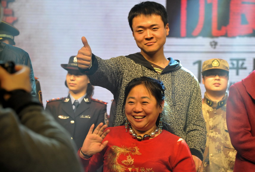 Fan Meng, who took his mother to travel on a wheel chair last year, poses for a photo with his mother at the ceremony that honors people with great virtue held in Beijing on Jan. 24, 2012. (Photo/Xinhua)