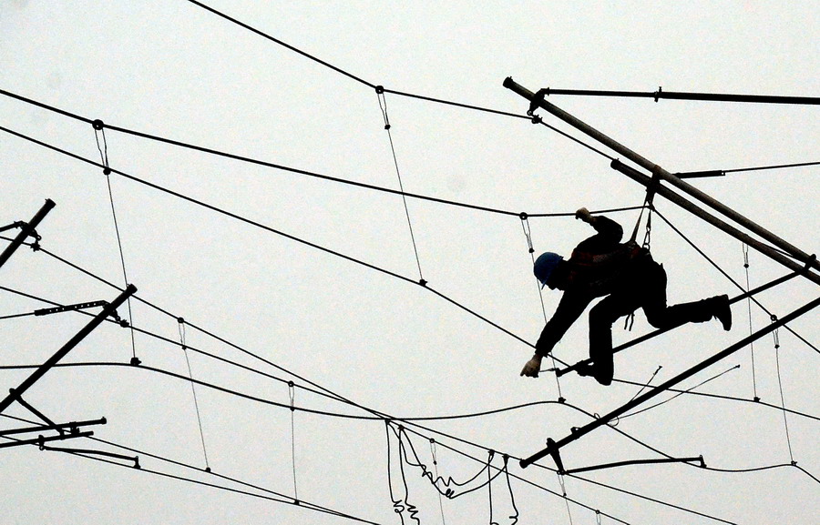 A worker demolishes contact line in smog on Jan 22, 2013. More than 260 workers constructed new contact lines in 27 sites in hard condition for the South-to-North Diversion project. (Photo/Xinhua)