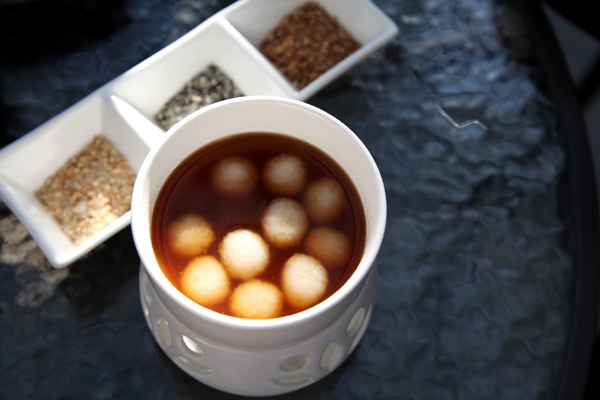 The rice ball fondue is a combination of glutinous rice balls floating in sugar syrup and a platter of dips, such as sugar and sesame and crushed peanuts. (Photo by Fan Zhen/China Daily)