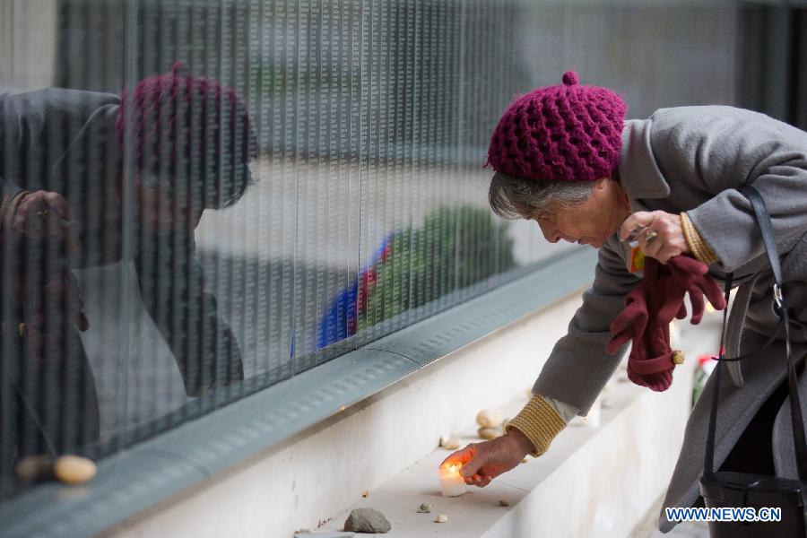 A woman lights a candle in front of a memorial wall at Budapest's Holocaust Memorial Centre in Budapest, Hungary, on the international Holocaust Remembrance Day of Jan. 27, 2013. The annual International Day was designated by a UN General Assembly resolution to fall each year on Jan. 27, the anniversary of the liberation of the Auschwitz death camp. (Xinhua/Attila Volgyi) 