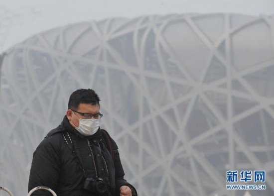 A mask-wearing man passes the National Stadium in the foggy weather, Jan. 13. Beijing's meteorological center on Monday issued a yellow-coded alert for haze as the fourth foggy weather in this month hit the city and cuts the visibility below 3,000 meters in major parts of Beijing. (Photo/Xinhua)