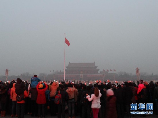 Tourists watches flag-raising ceremony at Tiananmen Square in the foggy weather, Jan. 23. Beijing's meteorological center on Monday issued a yellow-coded alert for haze as the fourth foggy weather in this month hit the city and cuts the visibility below 3,000 meters in major parts of Beijing. (Photo/Xinhua)