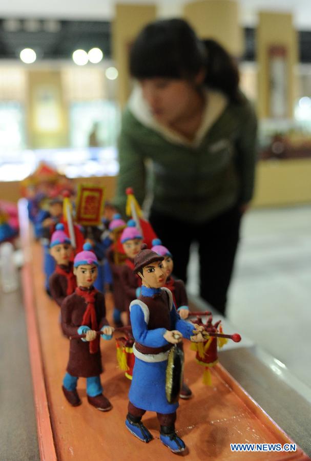 A visitor looks at clay sculptures during an exhibition of traditional culture in Shijiazhuang, capital of north China's Hebei Province, Jan. 28, 2013. An 8-day exhibition in celebration of the coming Spring Festival was held in Shijiazhuang on Monday. (Xinhua/Zhu Xudong)