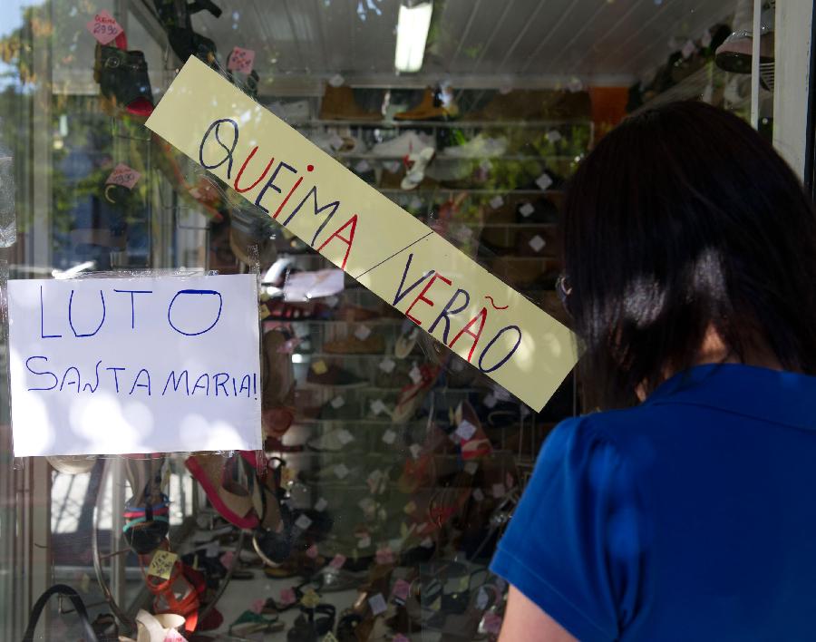 A post saying "Mourn Santa Maria" is seen on the window of a closing shop in central Santa Maria, Brazil, on Jan. 28, 2013.  (Xinhua/Weng Xinyang) 