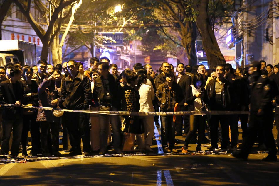 A photo taken on Jan. 28 shows the onlookers behind the security cordon. Several buildings collapsed on Monday afternoon after a subsidence at a road junction in Liwan district of downtown Guangzhou. The subsidence occurred again at around 9 p.m. (Photo/Image China)