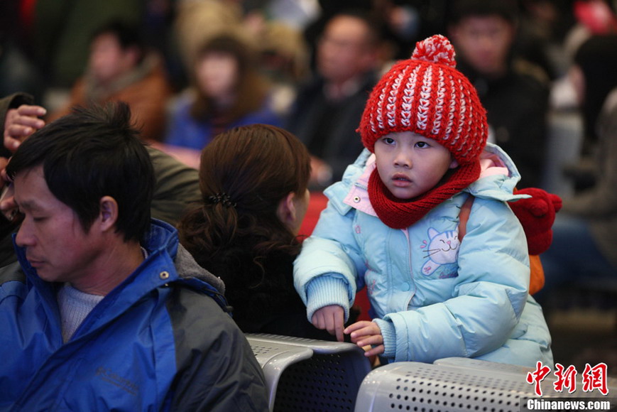 A young traveler wears a red hat with his family in the waiting hall of railway station on Jan. 26, 2013. (CNS/XU Chongde)