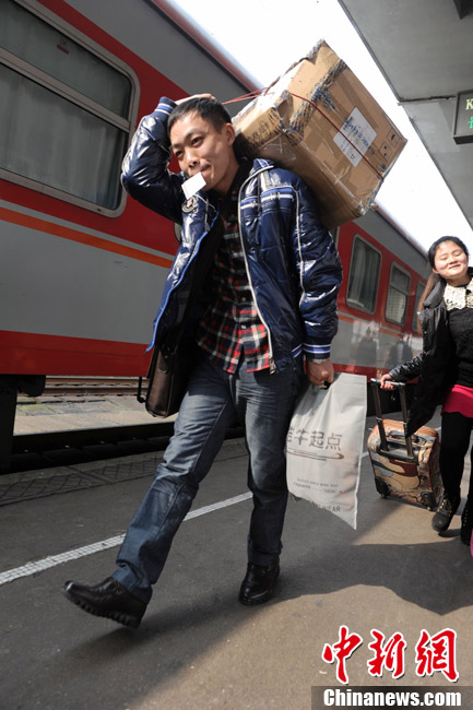 A hard journey home: A traveler carrying a bag and holding train ticket in the mouth runs to get on train at Changsha South Railway Station on Jan. 26, 2013. (CNS/Yang Huafeng)