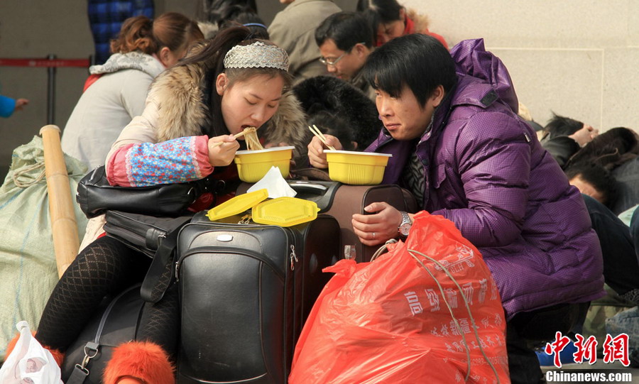 Temporary dining table: Travelers eat instant noodles on their luggage in the waiting hall on Jan. 26, 2013. (CNS/Zhang Chang)