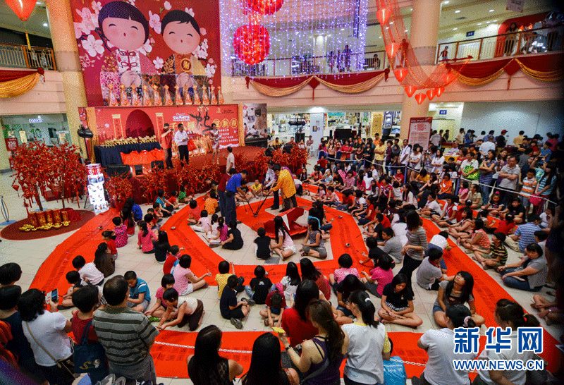 Contestants write down the Chinese character "she", meaning snake, on the piece of red paper with writing brush on Sunday in Selangor, Malaysia. (Xinhua Photo by Zhang Wenzong)