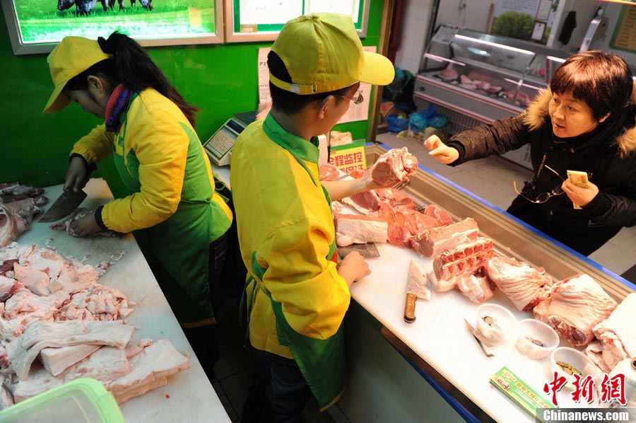 Hao Chengbin (R), a graduate from Jiangxi University of Finance and Economics, and Sun Xia (L), a graduate from University of Hainan, work at a "No.1 Pork" butcher shop in Shanghai on Jan. 29, 2013.(Photo/CNS)