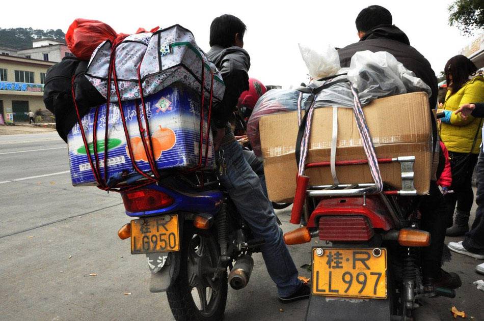 Migrant workers who are on the way home by motorbike take short rest at a highway toll station in Fengkai county, south China's Guangdong province, Jan. 30. On Wednesday, about 5,000 motorbikes taking migrant workers home from Guangdong run into the neighboring Guangxi Zhuang Autonomous Region for the upcoming Spring Festival. Traffic police said about 3,000 such bikes passed through the county every day thanks to the well-developed roads connecting Guangxi and Guangdong. Local government offered free services including police escort, food, beverage and medical care to these homecoming people on the motorbike. (Photo/Image China)