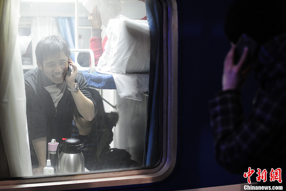 Even on the train, Lin still keeps in touch by phone with the classmates who say goodbye to him from outside. (Chinanews/Cui Nan)