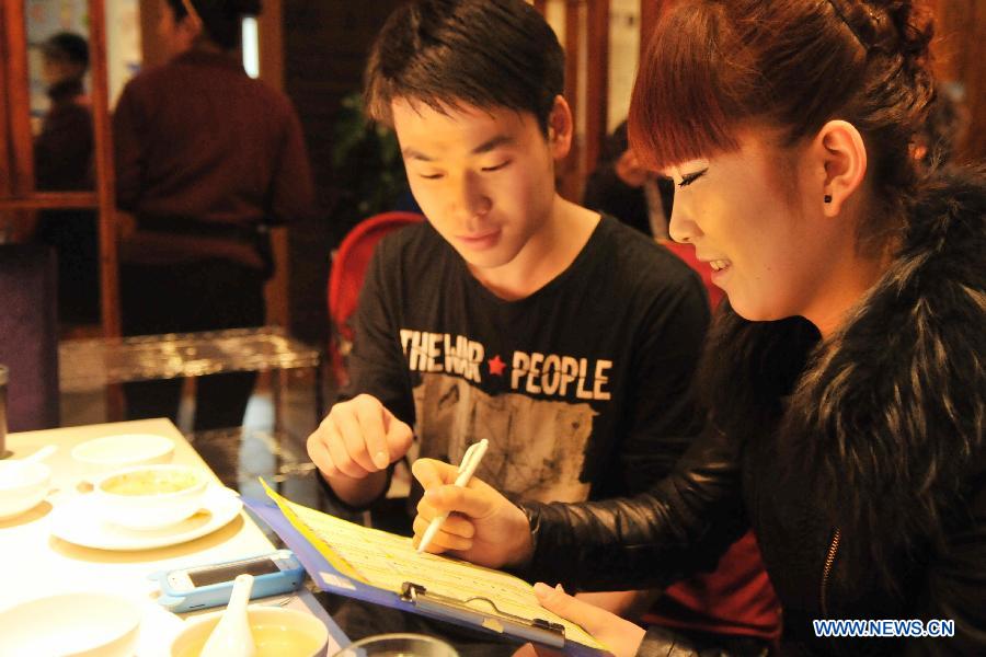 Customers order at a hot pot restaurant in Lanzhou, capital of northwest China's Gansu Province, Jan. 30, 2013. A "half portion, half price" activity was launched by numerous hot pot restaurant to advocate saving here Wednesday. (Xinhua/Chen Bin)