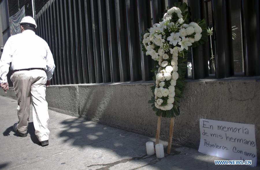 An engineer walks past a cross made of flowers outside the building of the explosion at the headquarters of Mexico's oil giant PEMEX, in Mexico City, capital of Mexico, on Feb. 2, 2013. Mexican and American experts carried out the research on reasons of the powerful explosion at the building E-B2 of the headquarters of Mexican oil giant Pemex, which caused the death of 33 people, injuring 121 others. (Xinhua/Shi Sisi)