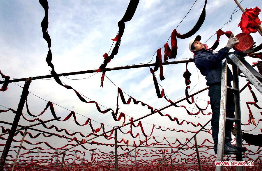 A young man hangs chains of firecrackers on a bank of the Yellow River in Zhengzhou, capital of central China's Henan Province, Feb. 3, 2005. The crackling and spluttering sound from firecrackers during the Spring Festival or Chinese Lunar New Year is expected to intimidate the Nian, a beast in Chinese mythology which comes out of hiding to attack people around Chinese New Year. Chinese people who live in the central China region have formed various traditions to celebrate the Chinese Lunar New Year. (Xinhua/Wang Song)
