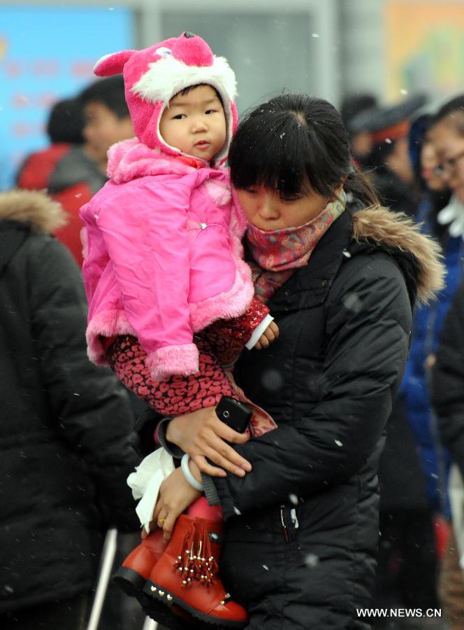 A woman carries her child at the Beijing West Railway Station in Beijing, capital of China, Feb. 3, 2013. Many children travel with their families during the 40-day Spring Festival travel rush which started on Jan. 26. (Xinhua/Chen Shugen)