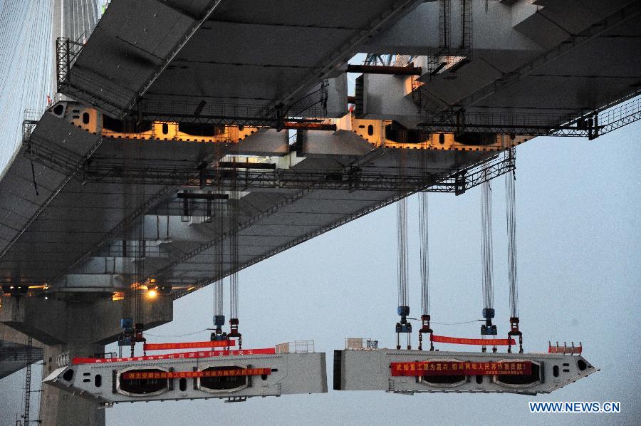Photo taken on Feb. 3, 2013 shows the last two steel box girders, each of which weighs 408 tons, are lifted up to the floor of the Jiaxing-Shaoxing Sea-Crossing Bridge in Shaoxing, east China's Zhejiang Province. The Jiaxing-Shaoxing Sea-Crossing Bridge, the 2nd sea-crossing bridge in Zhejiang , will be the world's longest and widest multi pylon cable-stayed bridge when it is finished. It is expected to halve the driving time from Shaoxing to Shanghai in east China after putting into use in June of 2013. (Xinhua/Xu Yu)